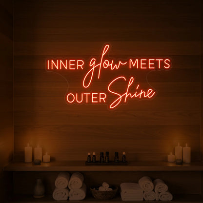 Photo of the 'INNER glow MEETS OUTER Shine' neon sign glowing in golden yellow against a styled interior wall.