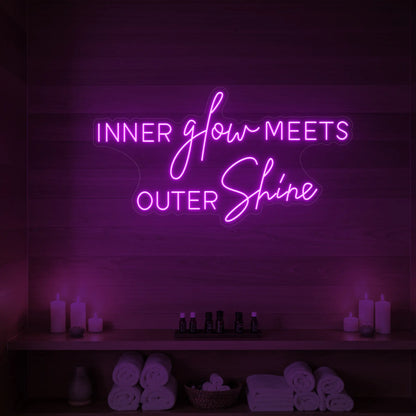 Photo of the 'INNER glow MEETS OUTER Shine' neon sign glowing in deep pink against a styled interior wall.