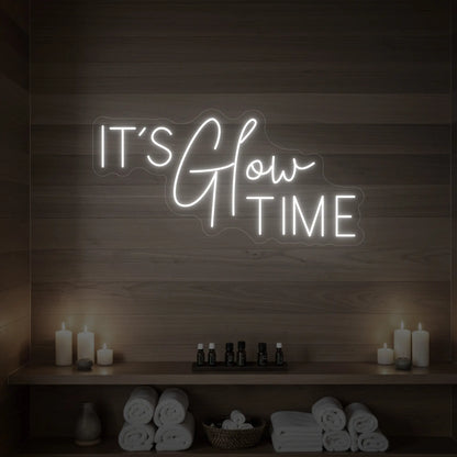 Photo of the 'IT’S Glow TIME' neon sign glowing in cool white against a styled interior wall.