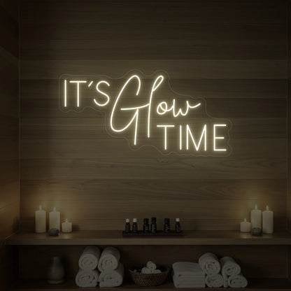 Photo of the 'IT’S Glow TIME' neon sign glowing in warm white against a styled interior wall.