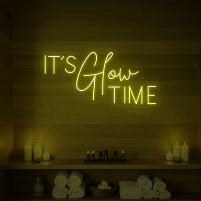 Photo of the 'IT’S Glow TIME' neon sign glowing in lemon yellow against a styled interior wall.
