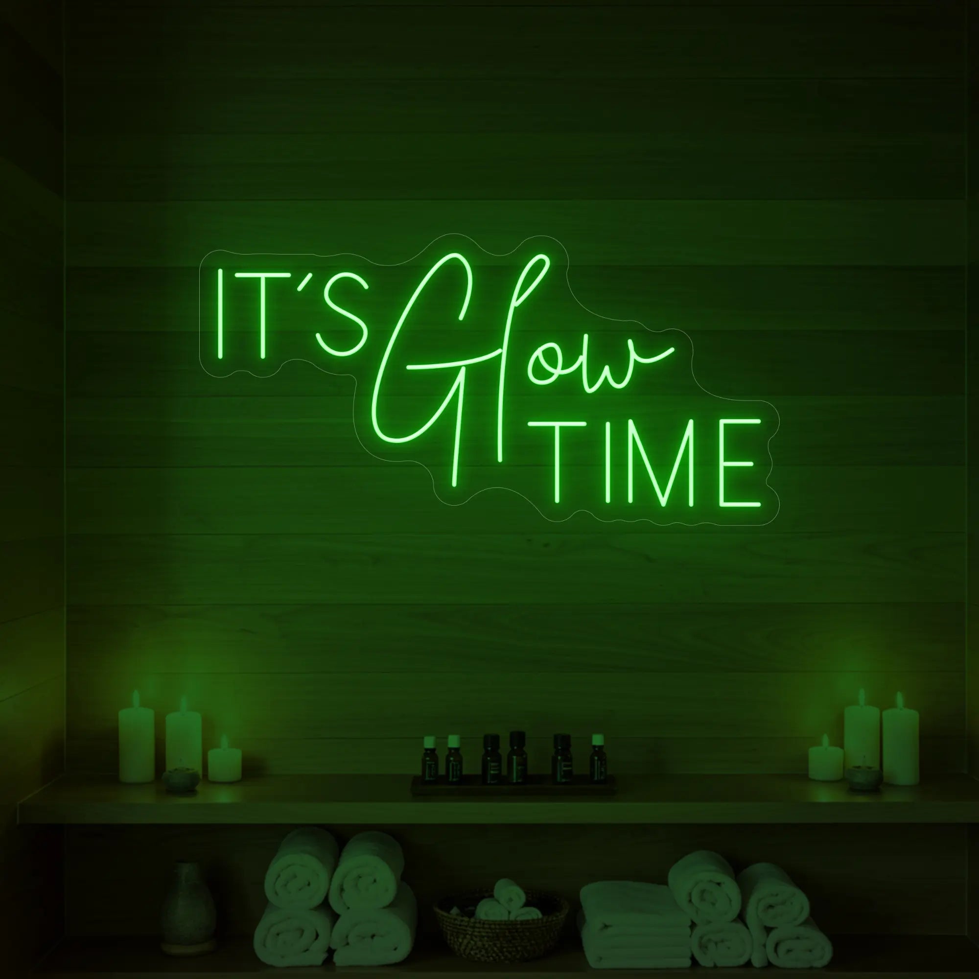Photo of the 'IT’S Glow TIME' neon sign glowing in green against a styled interior wall.