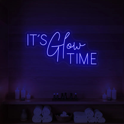 Photo of the 'IT’S Glow TIME' neon sign glowing in deep blue against a styled interior wall.