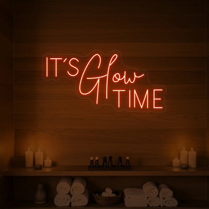 Photo of the 'IT’S Glow TIME' neon sign glowing in golden yellow against a styled interior wall.