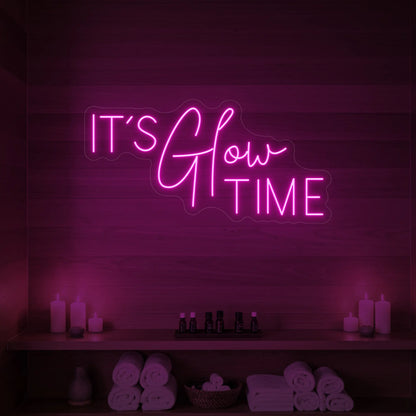 Photo of the 'IT’S Glow TIME' neon sign glowing in light pink against a styled interior wall.