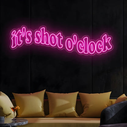 Photo of the 'It’s Shot O’Clock' neon sign glowing in deep pink against a styled interior wall.