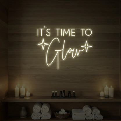 Photo of the 'IT’S TIME TO Glow' neon sign with sparkle icons glowing in warm white against a styled interior wall.