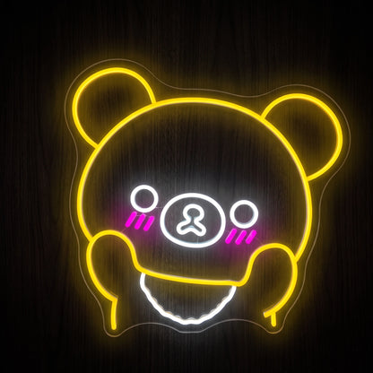 Kawaii bear face LED neon sign with yellow outline, cool white details and pink cheeks on clear acrylic backing.