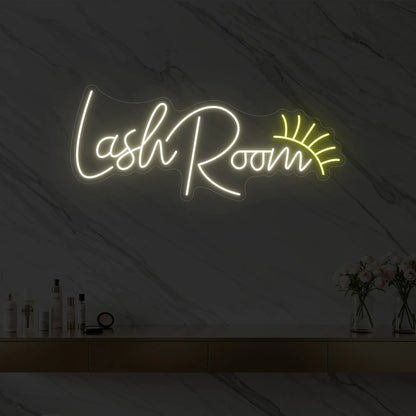 Photo of the 'Lash Room' neon sign with an eyelash icon glowing in warm white against a styled interior wall.