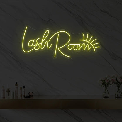 Photo of the 'Lash Room' neon sign with an eyelash icon glowing in lemon yellow against a styled interior wall.