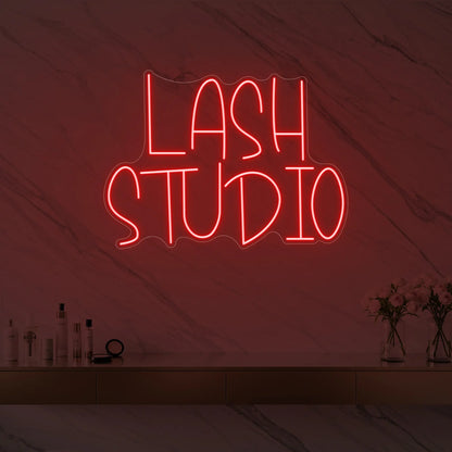 Photo of the 'LASH STUDIO' neon sign glowing in red against a styled interior wall.