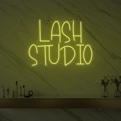 Photo of the 'LASH STUDIO' neon sign glowing in lemon yellow against a styled interior wall.