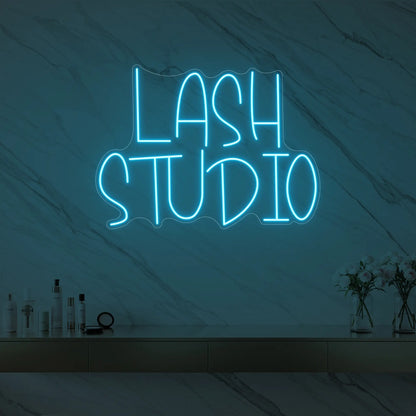 Photo of the 'LASH STUDIO' neon sign glowing in ice blue against a styled interior wall.