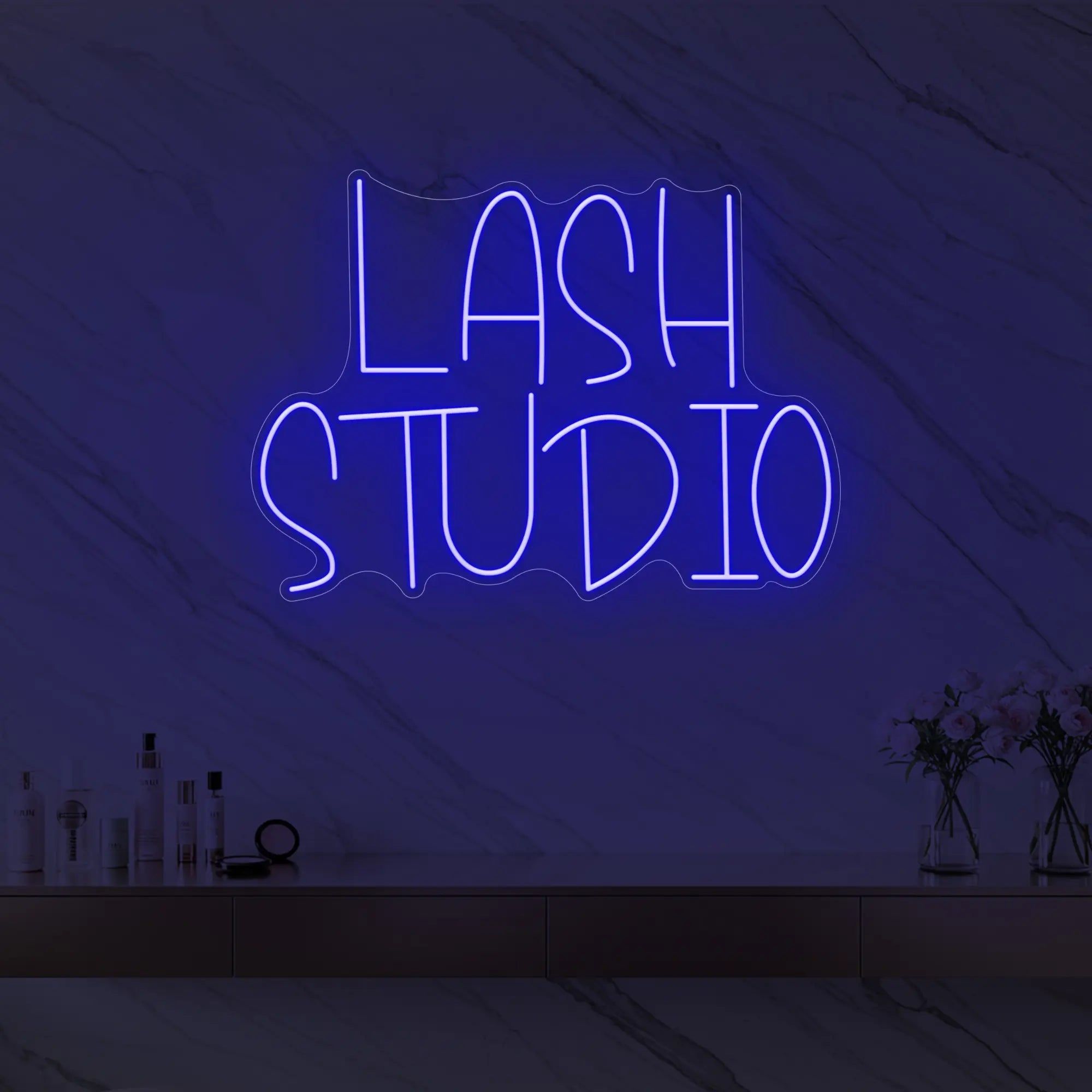 Photo of the 'LASH STUDIO' neon sign glowing in deep blue against a styled interior wall.