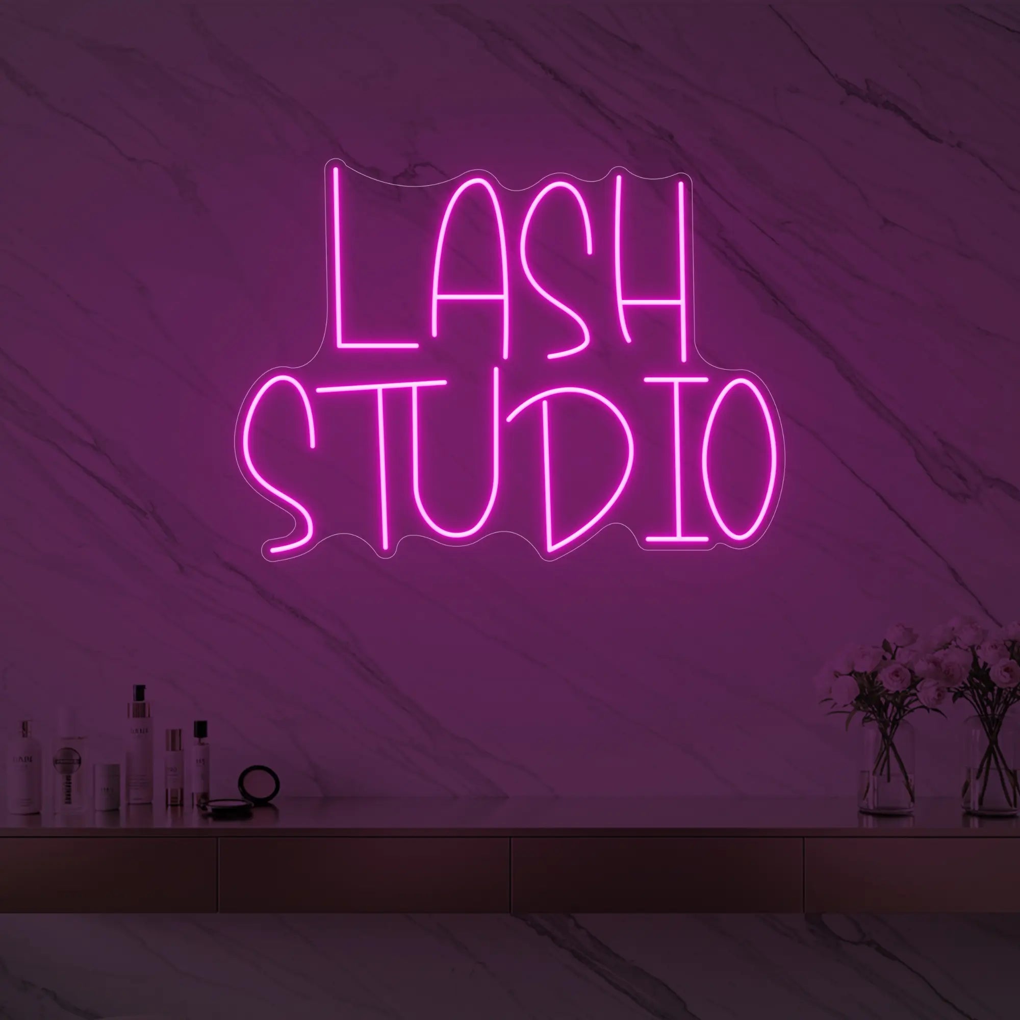 Photo of the 'LASH STUDIO' neon sign glowing in light pink against a styled interior wall.