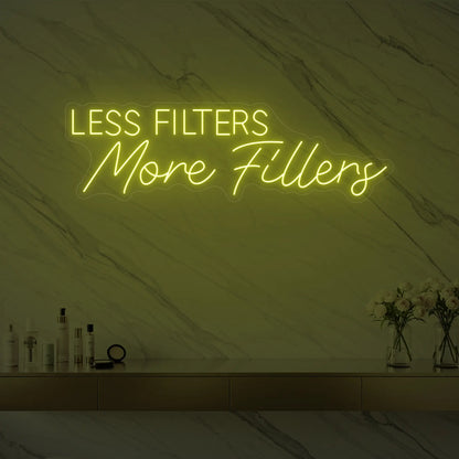 Photo of the 'LESS FILTERS MORE FILLERS' neon sign glowing in lemon yellow against a marble wall.
