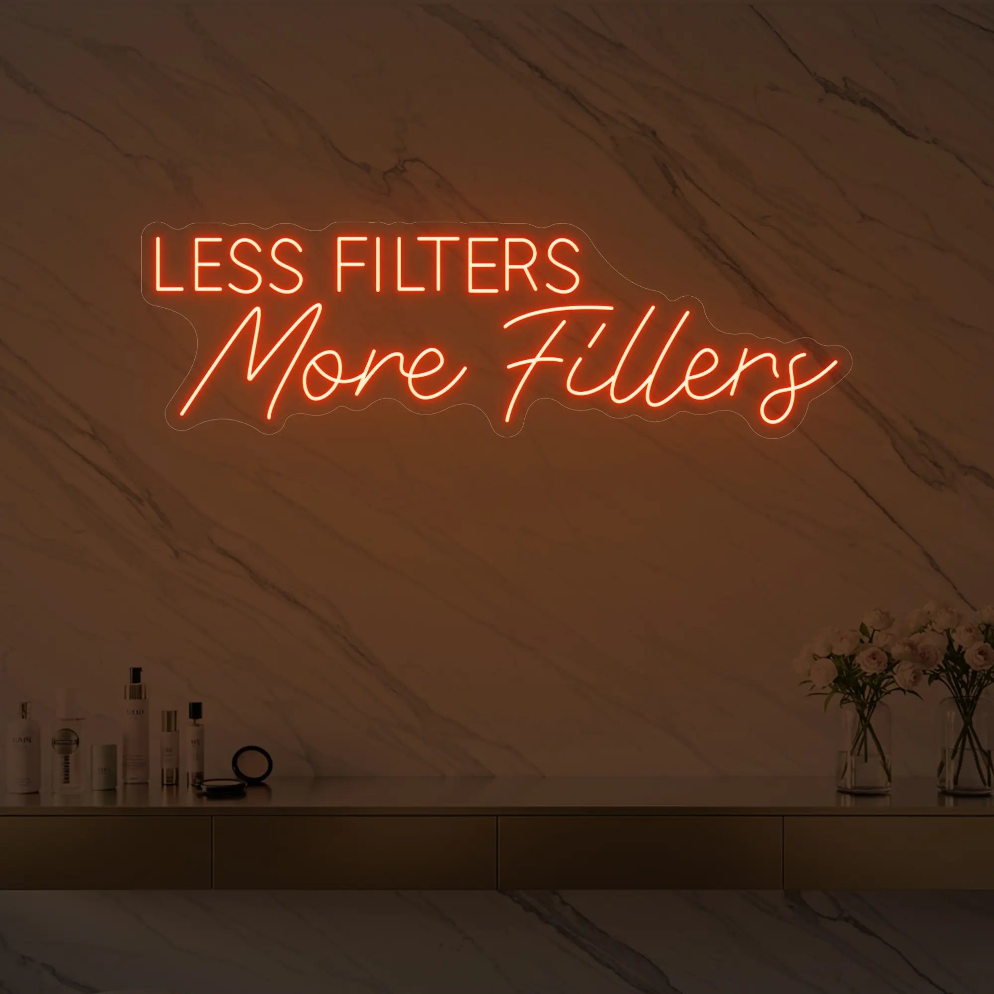 Photo of the 'LESS FILTERS MORE FILLERS' neon sign glowing in golden yellow against a marble wall.
