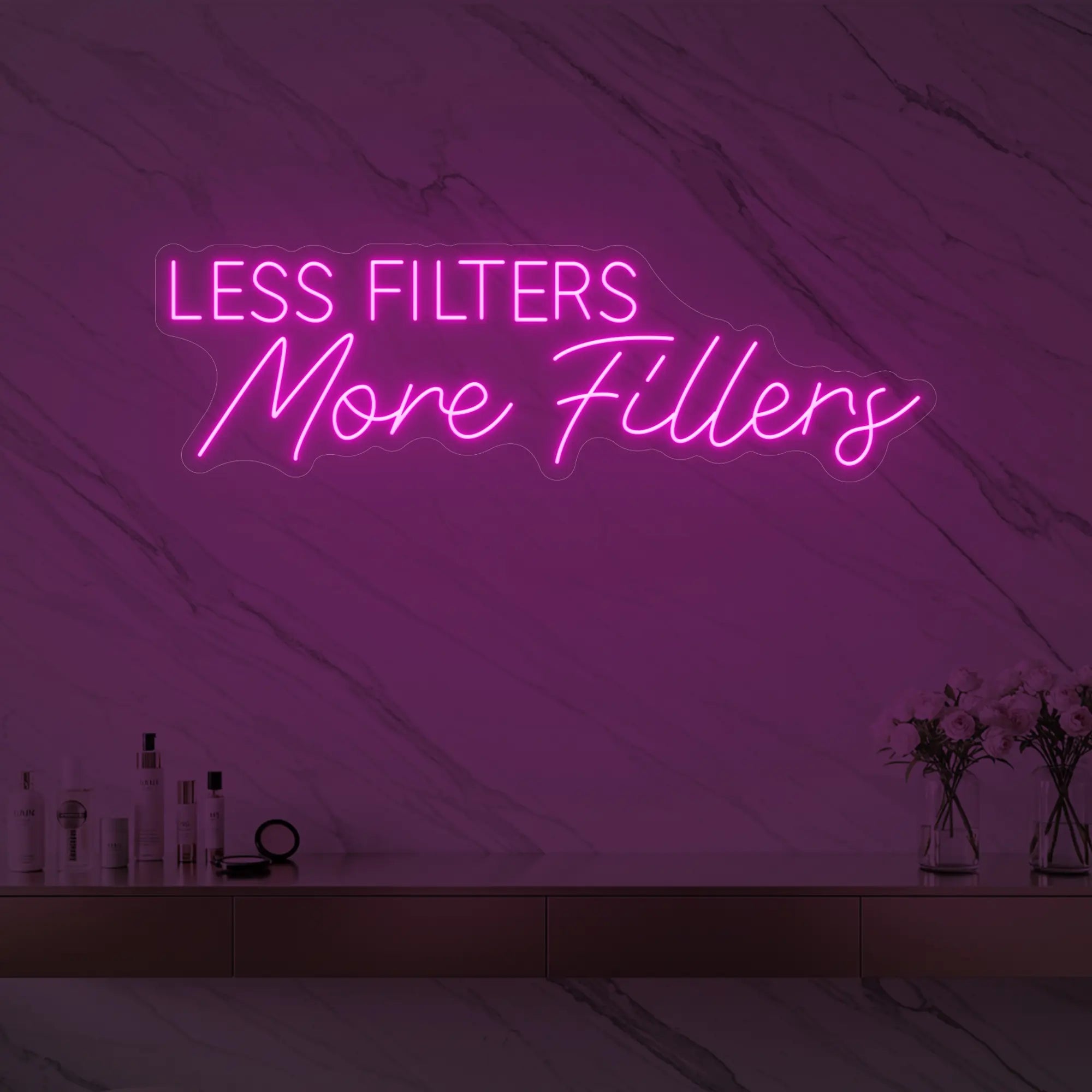 Photo of the 'LESS FILTERS MORE FILLERS' neon sign glowing in light pink against a marble wall.