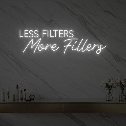 Photo of the 'LESS FILTERS MORE FILLERS' neon sign glowing in cool white against a marble wall.