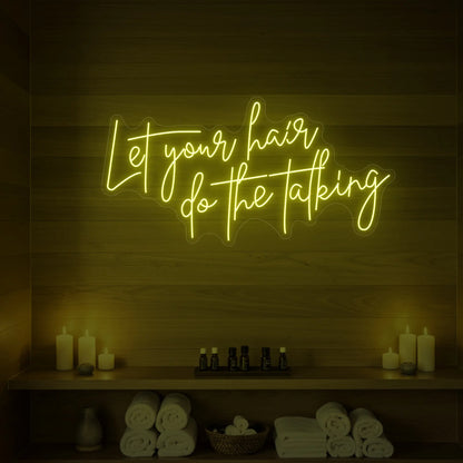Photo of the 'Let your hair do the talking' neon sign glowing in lemon yellow against a wooden wall.