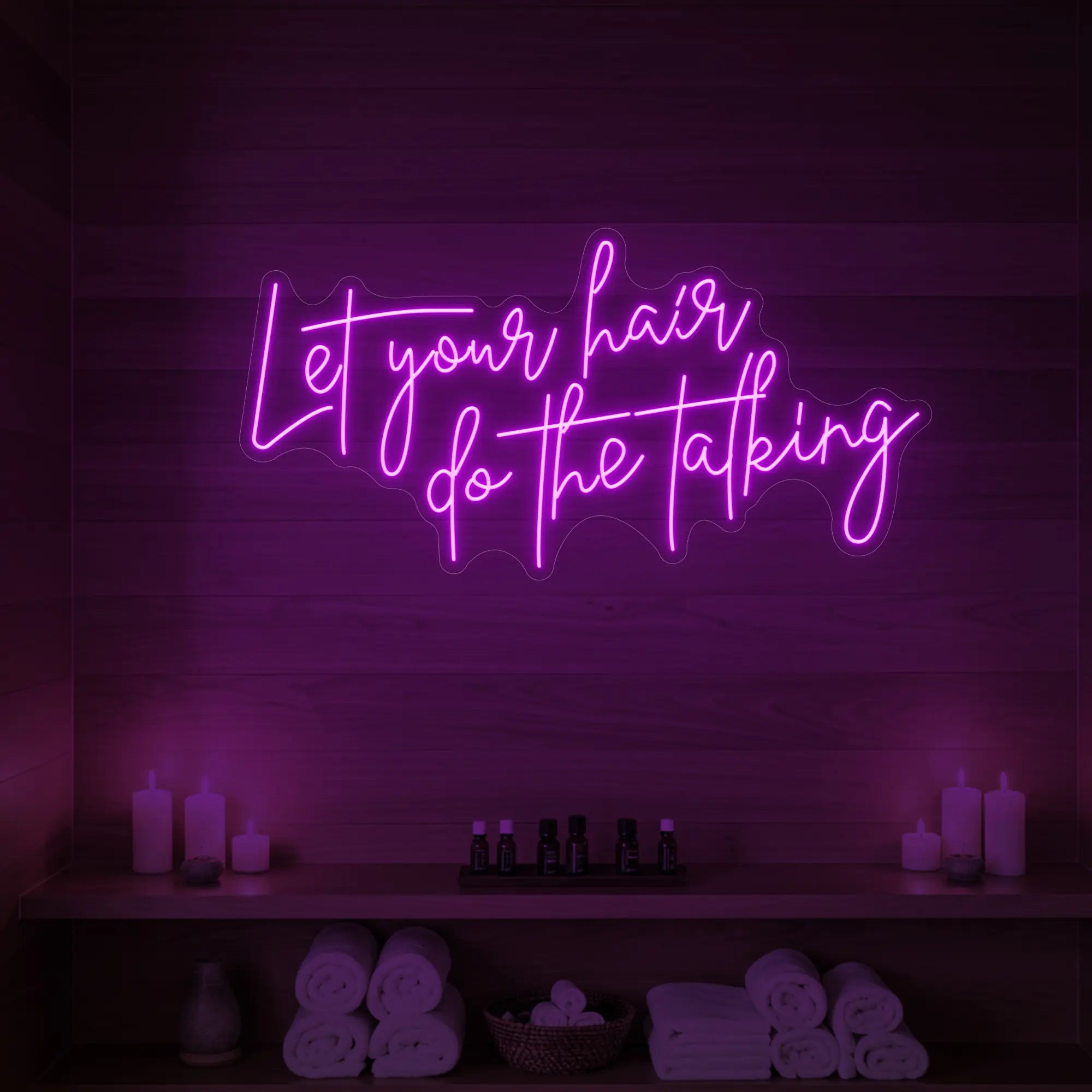 Photo of the 'Let your hair do the talking' neon sign glowing in deep pink against a wooden wall.