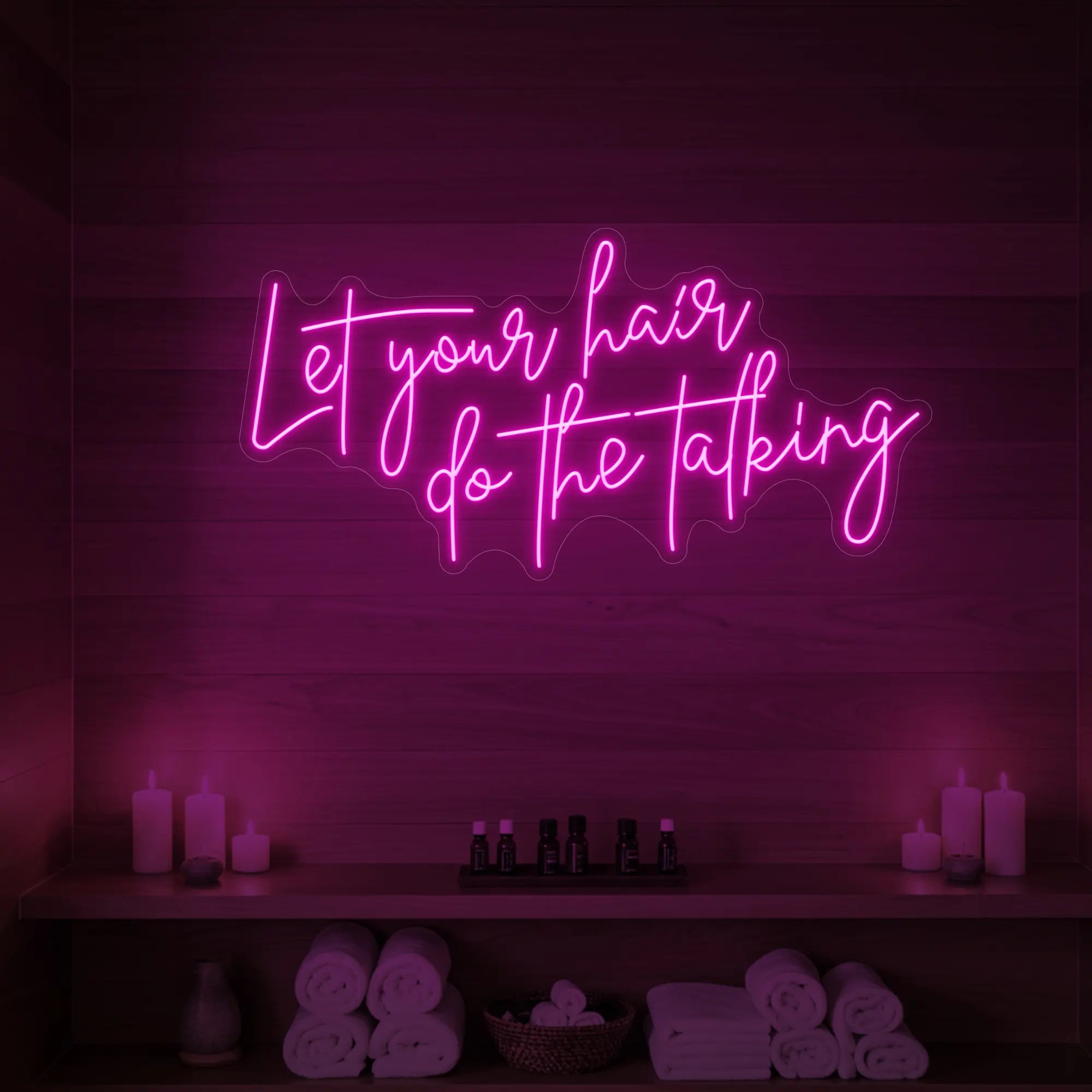 Photo of the 'Let your hair do the talking' neon sign glowing in light pink against a wooden wall.