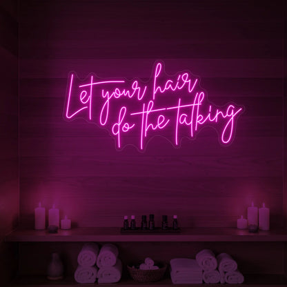 Photo of the 'Let your hair do the talking' neon sign glowing in light pink against a wooden wall.