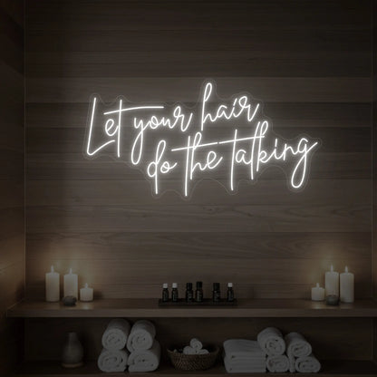 Photo of the 'Let your hair do the talking' neon sign glowing in cool white against a wooden wall.