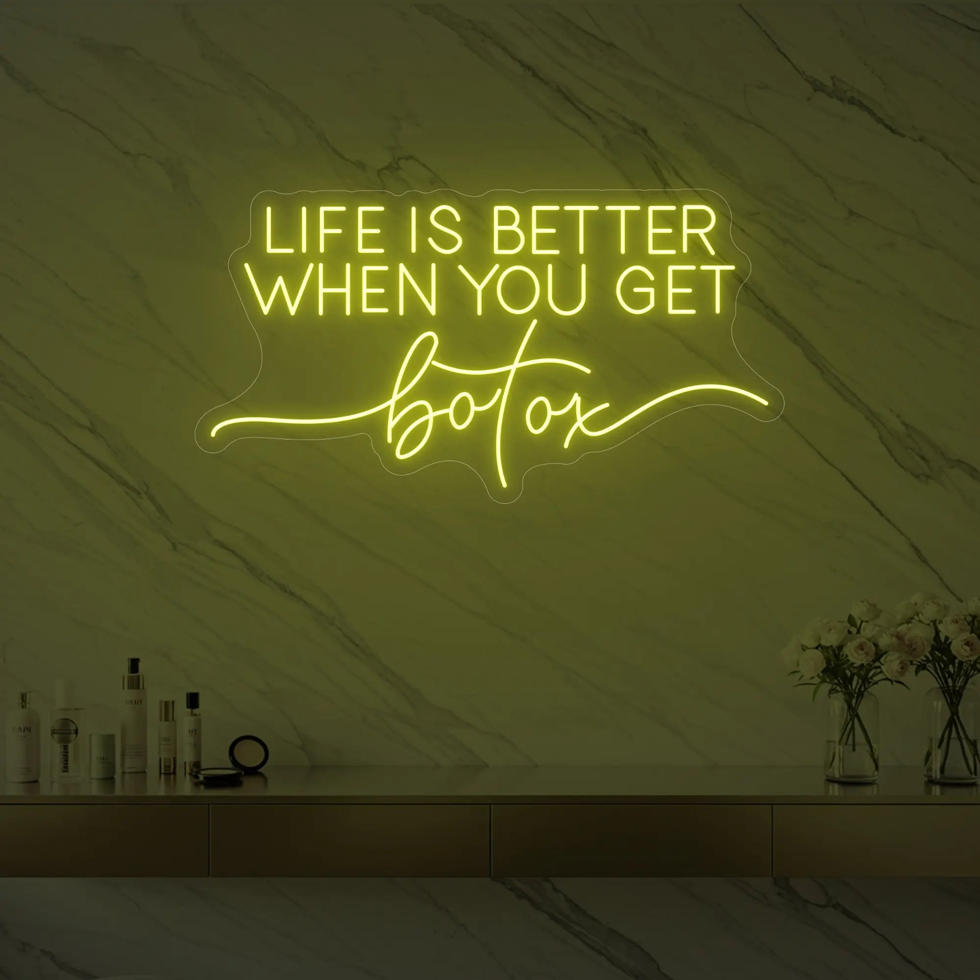 Photo of the 'Life is Better When You Get Botox' neon sign glowing in lemon yellow against a styled interior wall.
