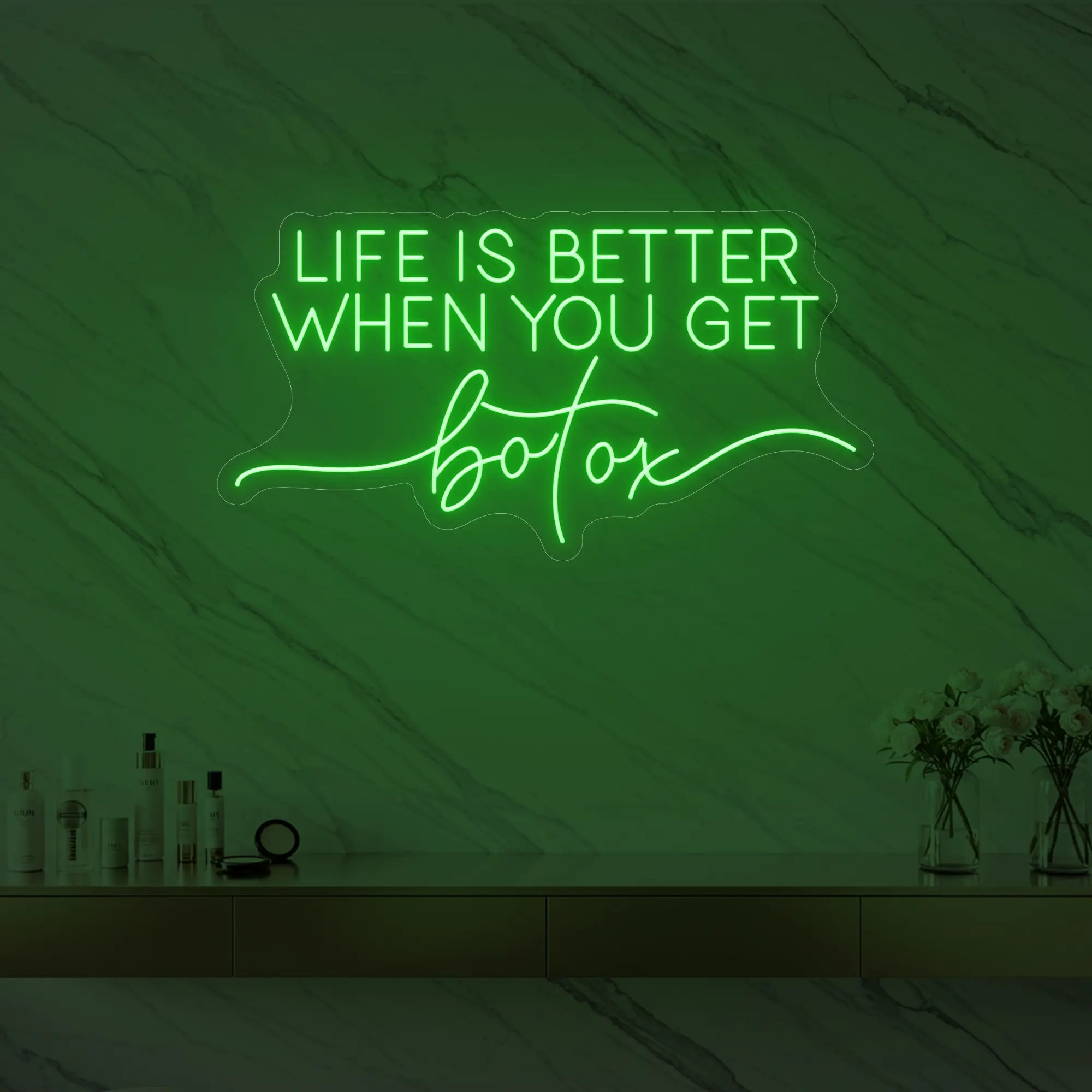 Photo of the 'Life is Better When You Get Botox' neon sign glowing in green against a styled interior wall.