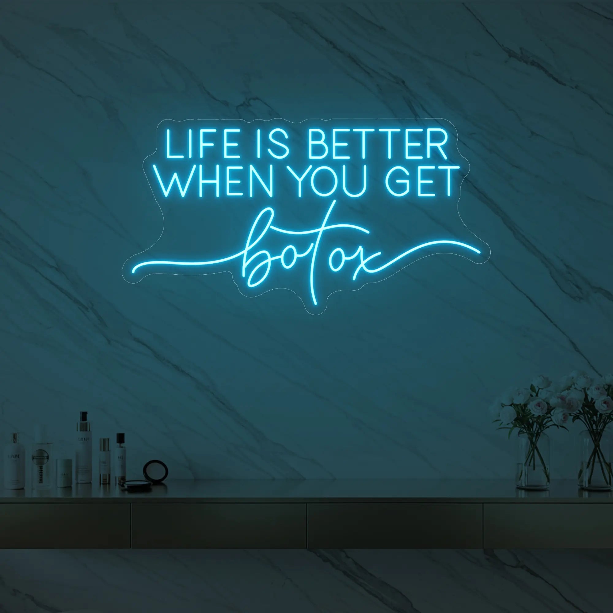 Photo of the 'Life is Better When You Get Botox' neon sign glowing in ice blue against a styled interior wall.