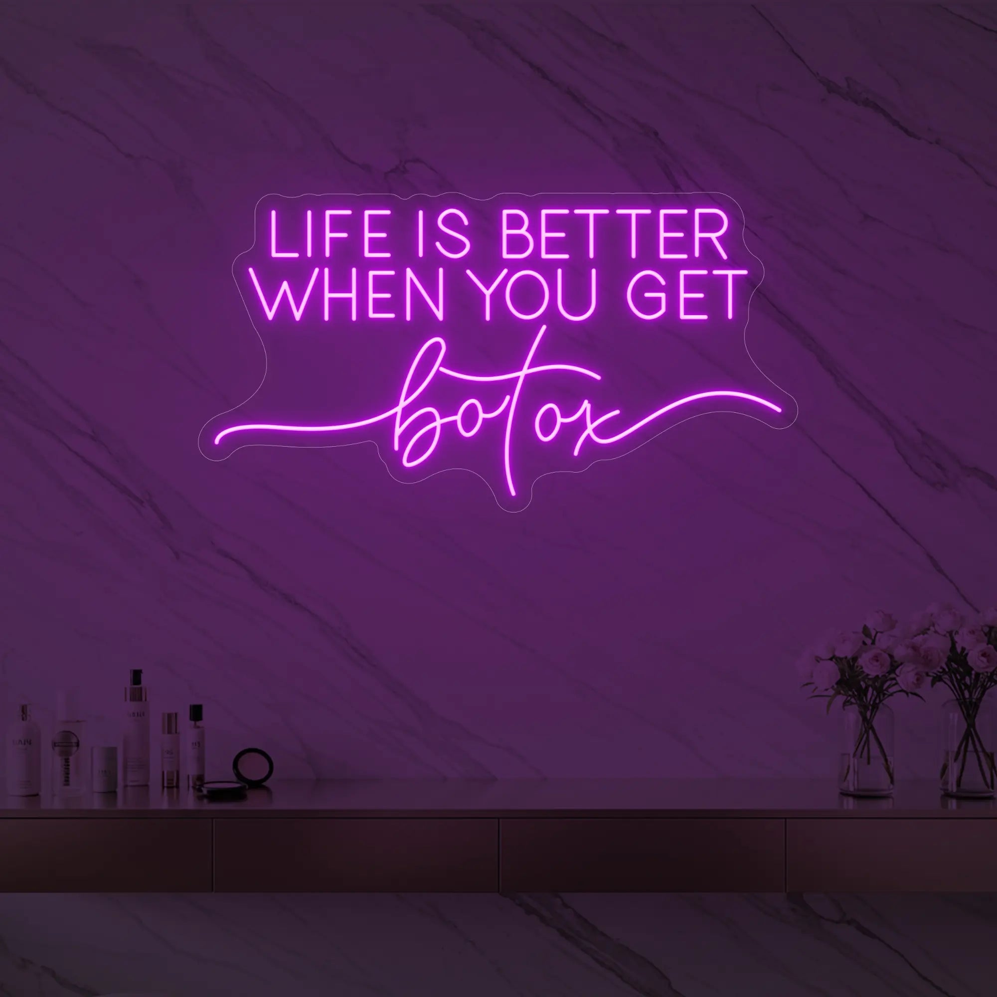 Photo of the 'Life is Better When You Get Botox' neon sign glowing in deep pink against a styled interior wall.
