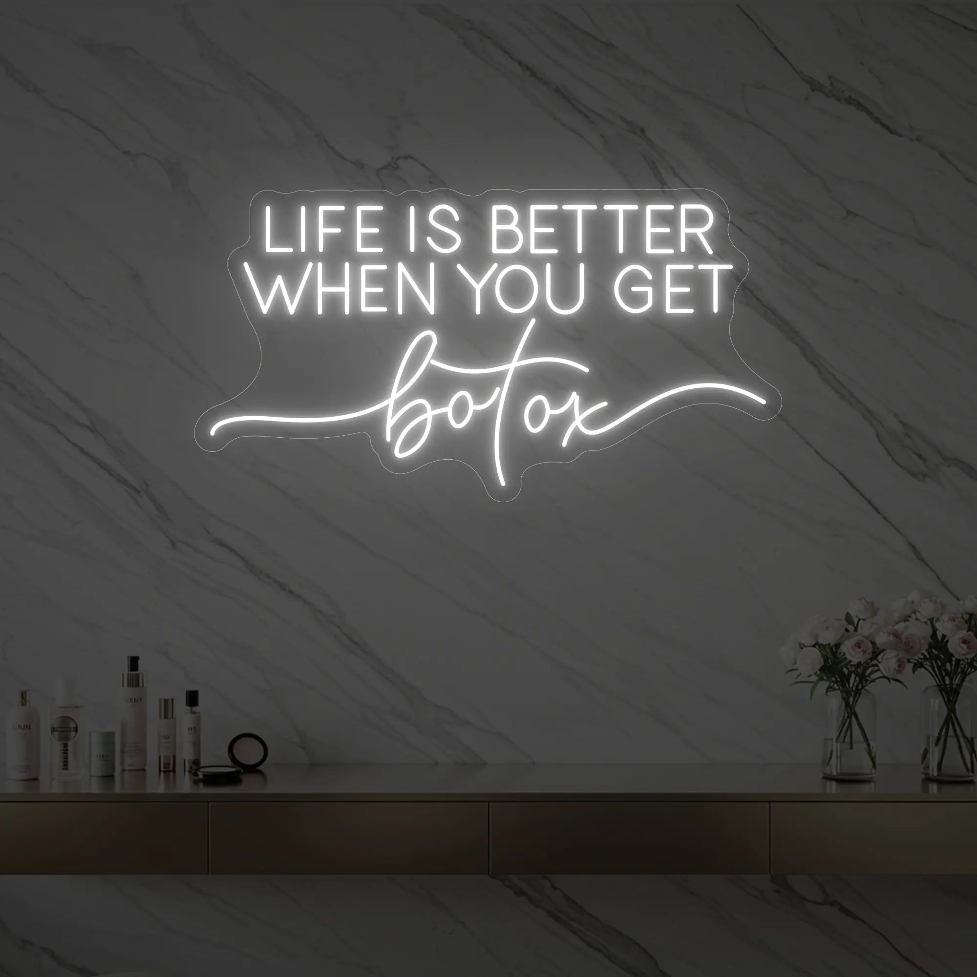 Photo of the 'Life is Better When You Get Botox' neon sign glowing in cool white against a styled interior wall.