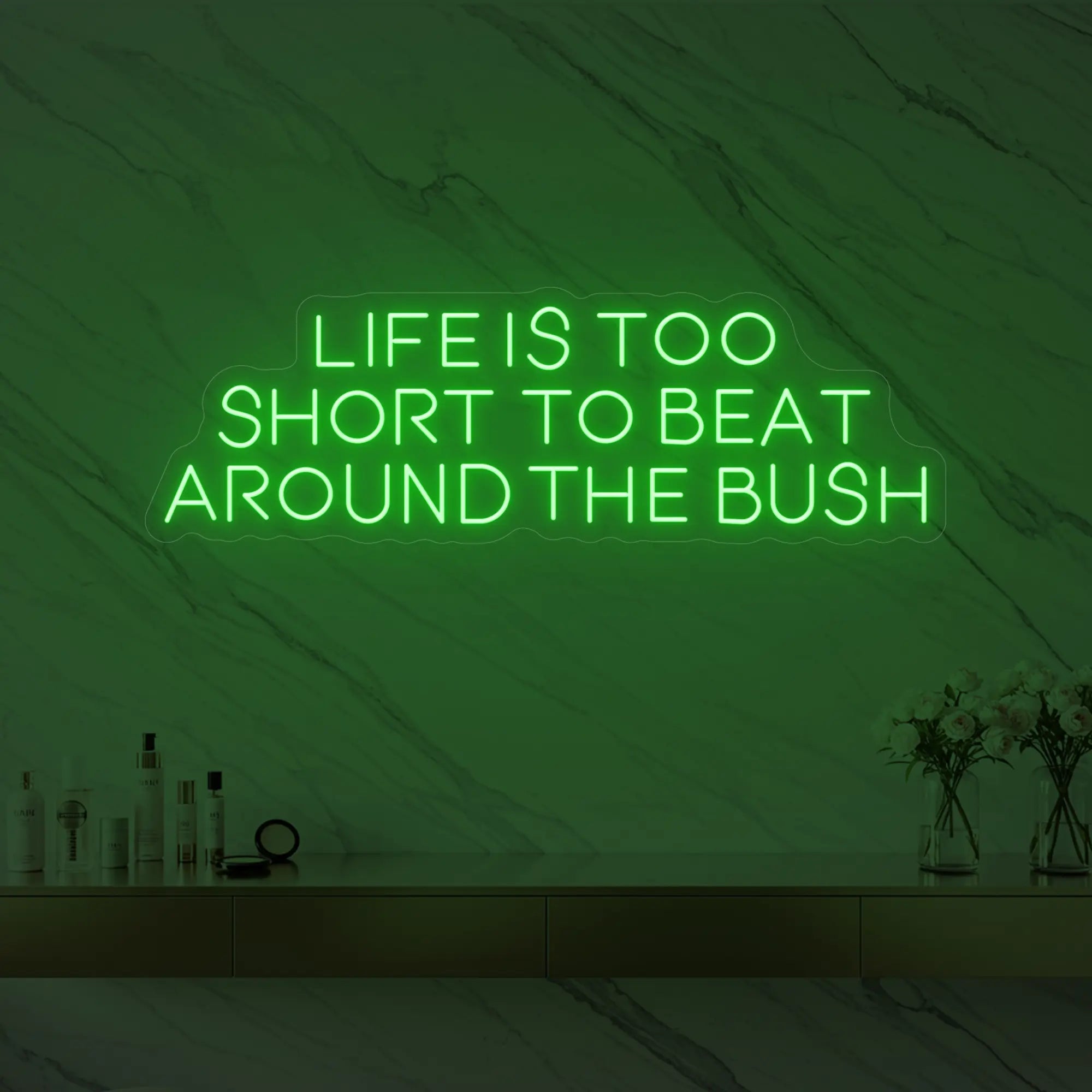 Photo of the 'Life is too short to beat around the bush' neon sign glowing in green against a marble wall.