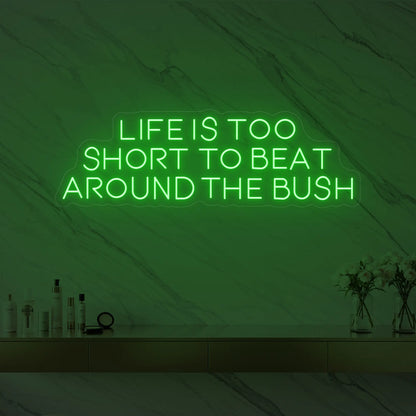 Photo of the 'Life is too short to beat around the bush' neon sign glowing in green against a marble wall.