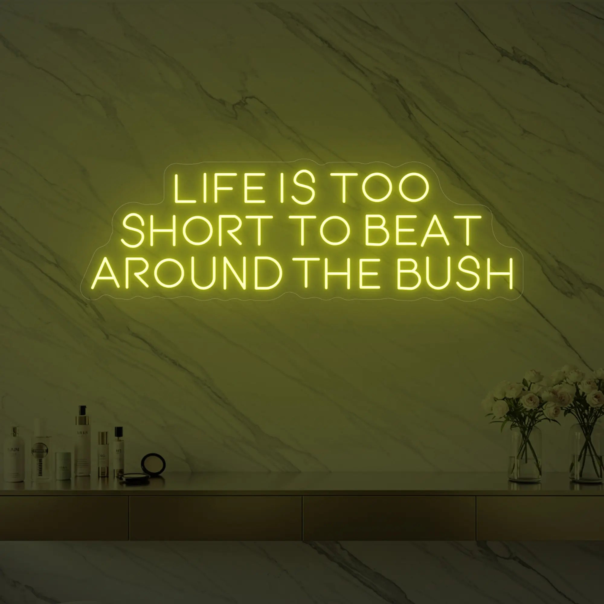 Photo of the 'Life is too short to beat around the bush' neon sign glowing in lemon yellow against a marble wall.