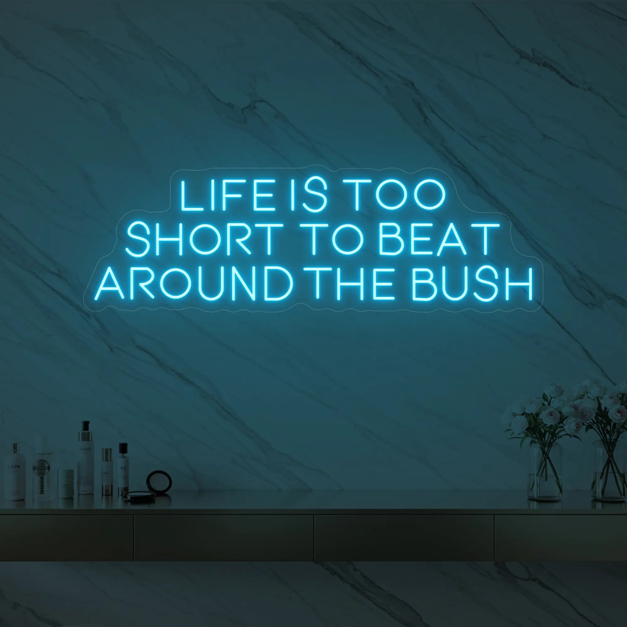 Photo of the 'Life is too short to beat around the bush' neon sign glowing in ice blue against a marble wall.