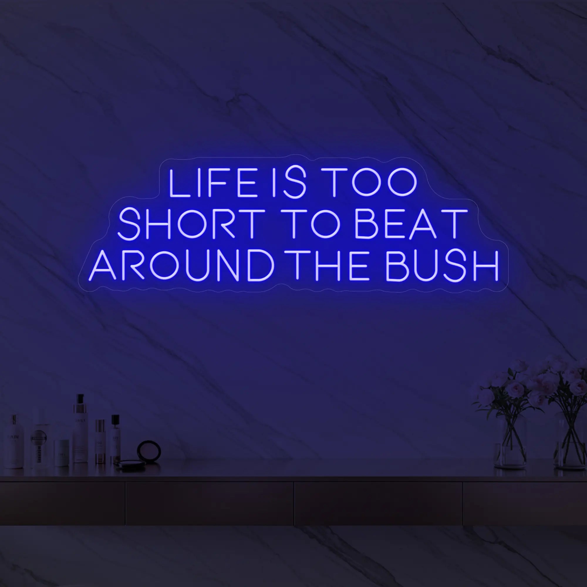 Photo of the 'Life is too short to beat around the bush' neon sign glowing in deep blue against a marble wall.