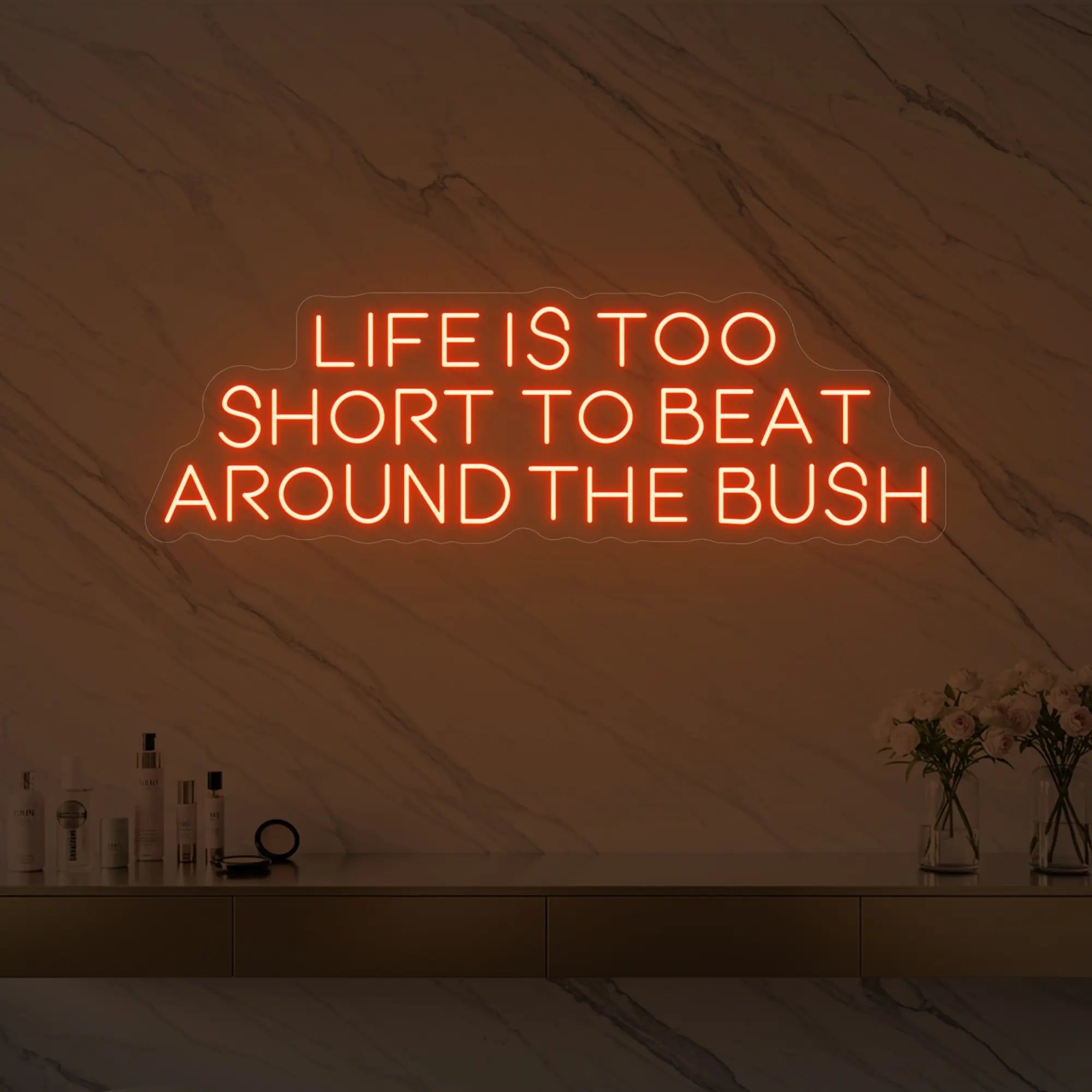 Photo of the 'Life is too short to beat around the bush' neon sign glowing in golden yellow against a marble wall.