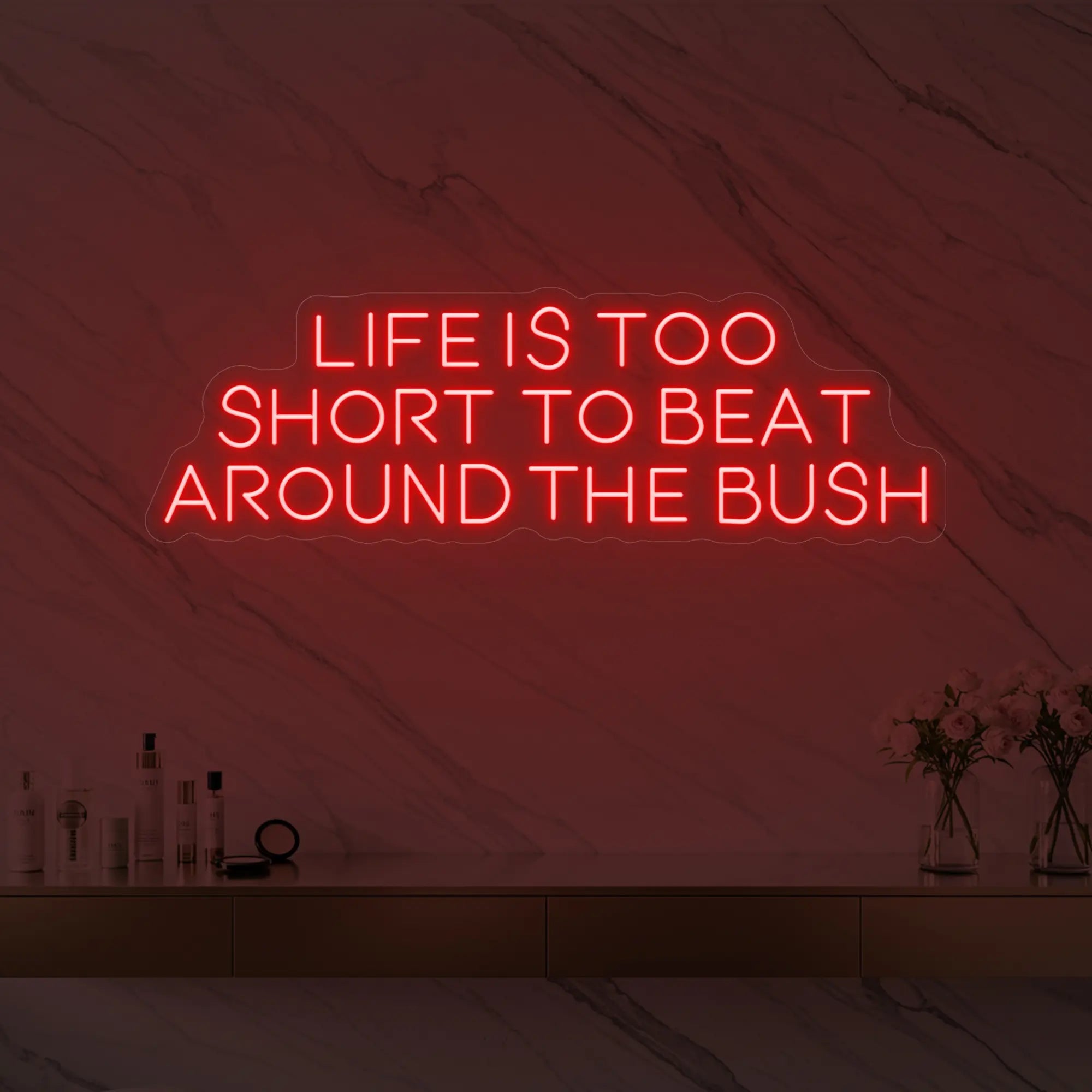Photo of the 'Life is too short to beat around the bush' neon sign glowing in red against a marble wall.
