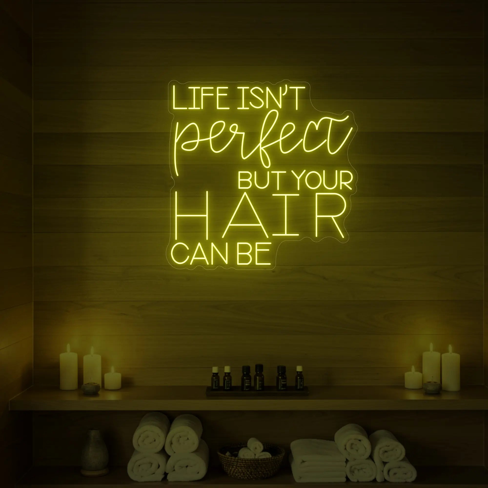 Photo of the 'Life isn’t perfect but your hair can be' neon sign glowing in lemon yellow against a wood-paneled spa wall.