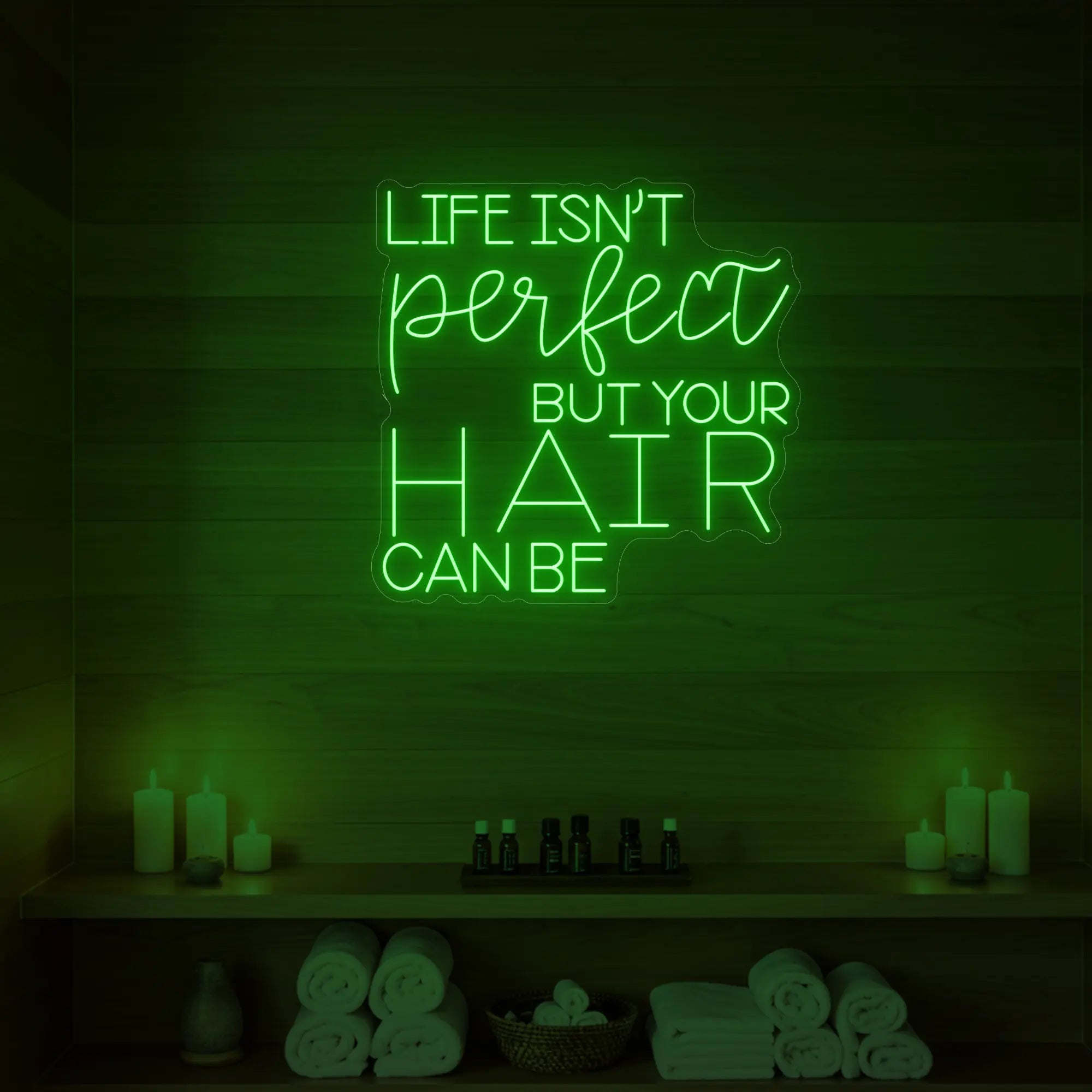 Photo of the 'Life isn’t perfect but your hair can be' neon sign glowing in green against a wood-paneled spa wall.