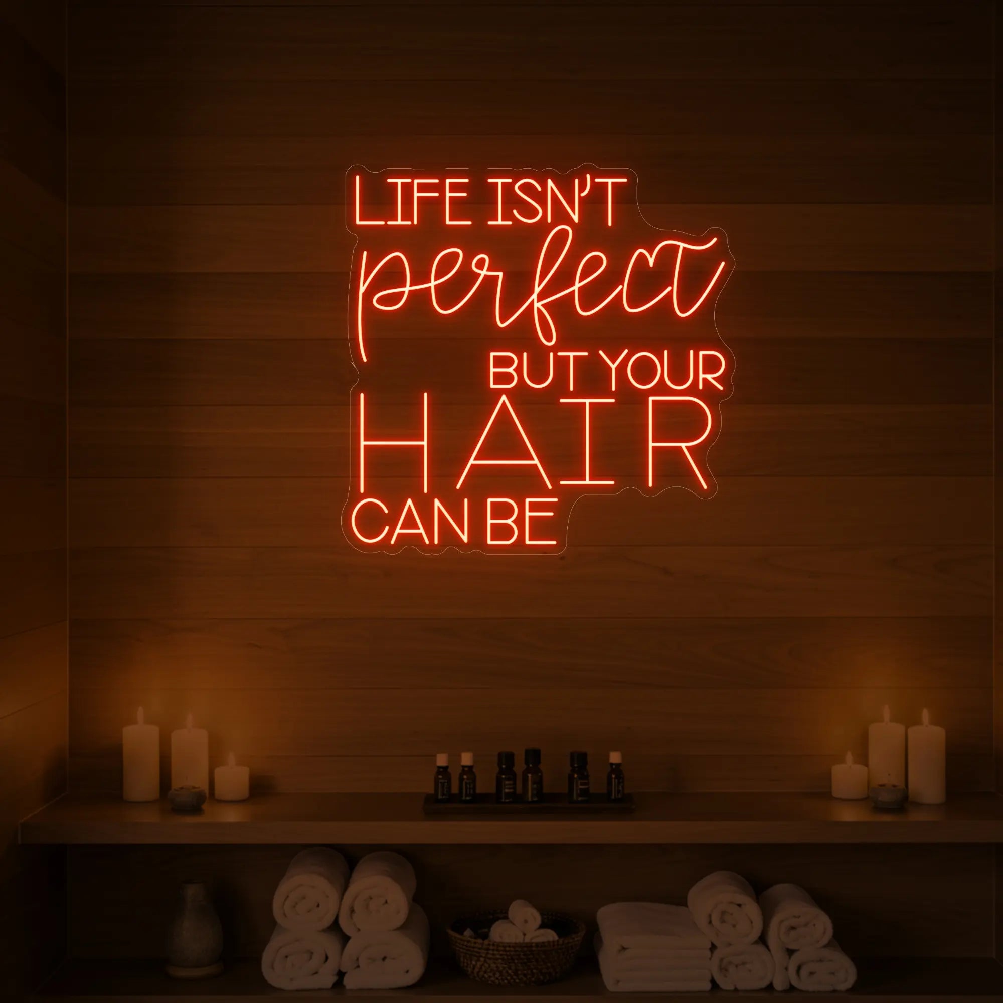 Photo of the 'Life isn’t perfect but your hair can be' neon sign glowing in golden yellow against a wood-paneled spa wall.