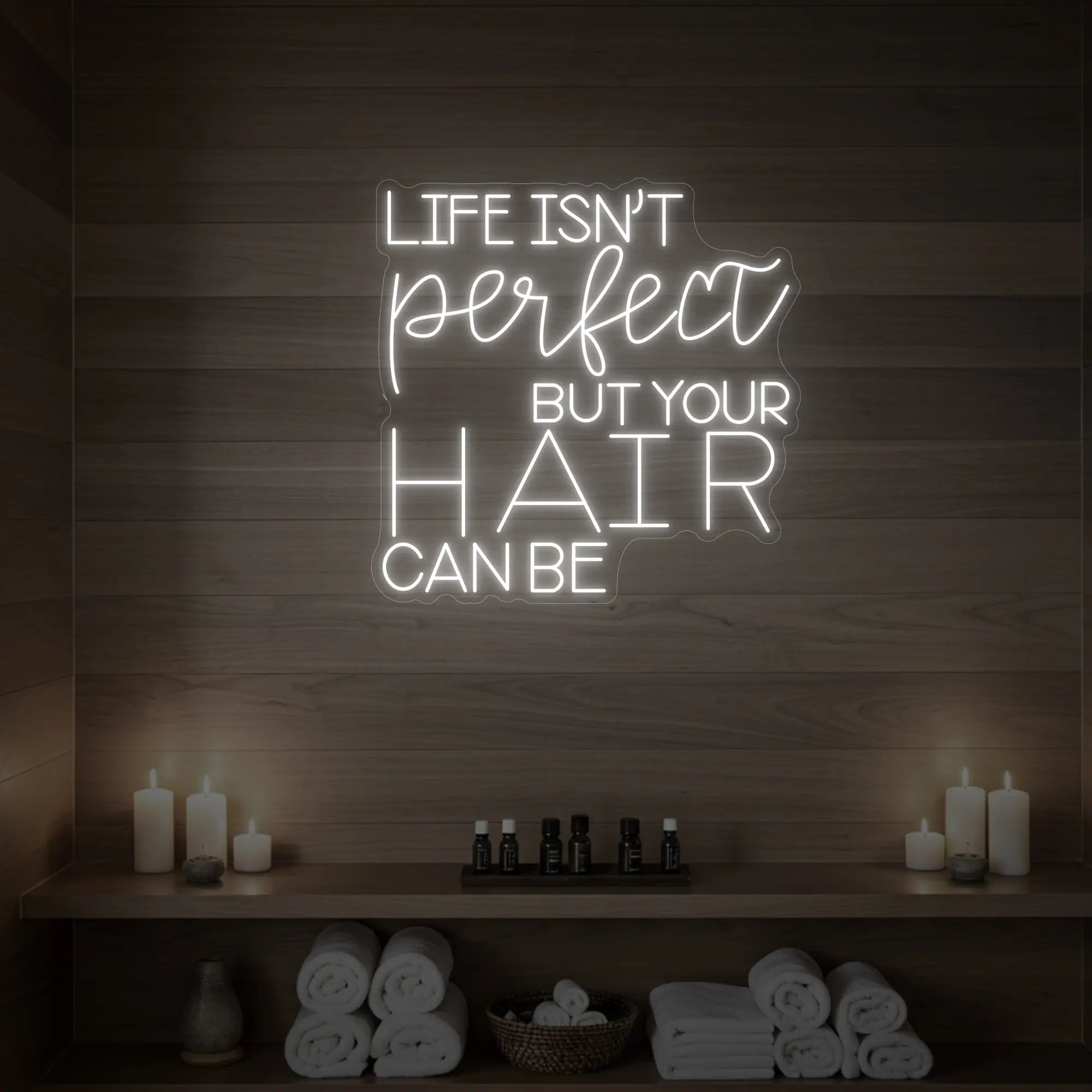 Photo of the 'Life isn’t perfect but your hair can be' neon sign glowing in cool white against a wood-paneled spa wall.