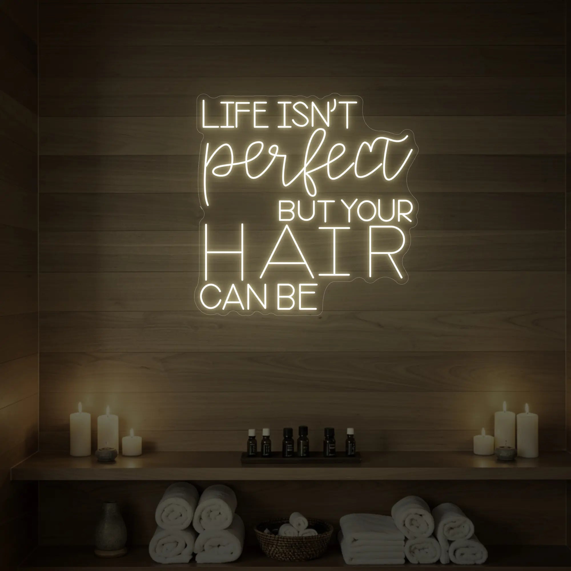 Photo of the 'Life isn’t perfect but your hair can be' neon sign glowing in warm white against a wood-paneled spa wall.