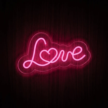 Love Script LED Neon Sign featuring pink cursive lettering with a heart detail on clear acrylic backing.