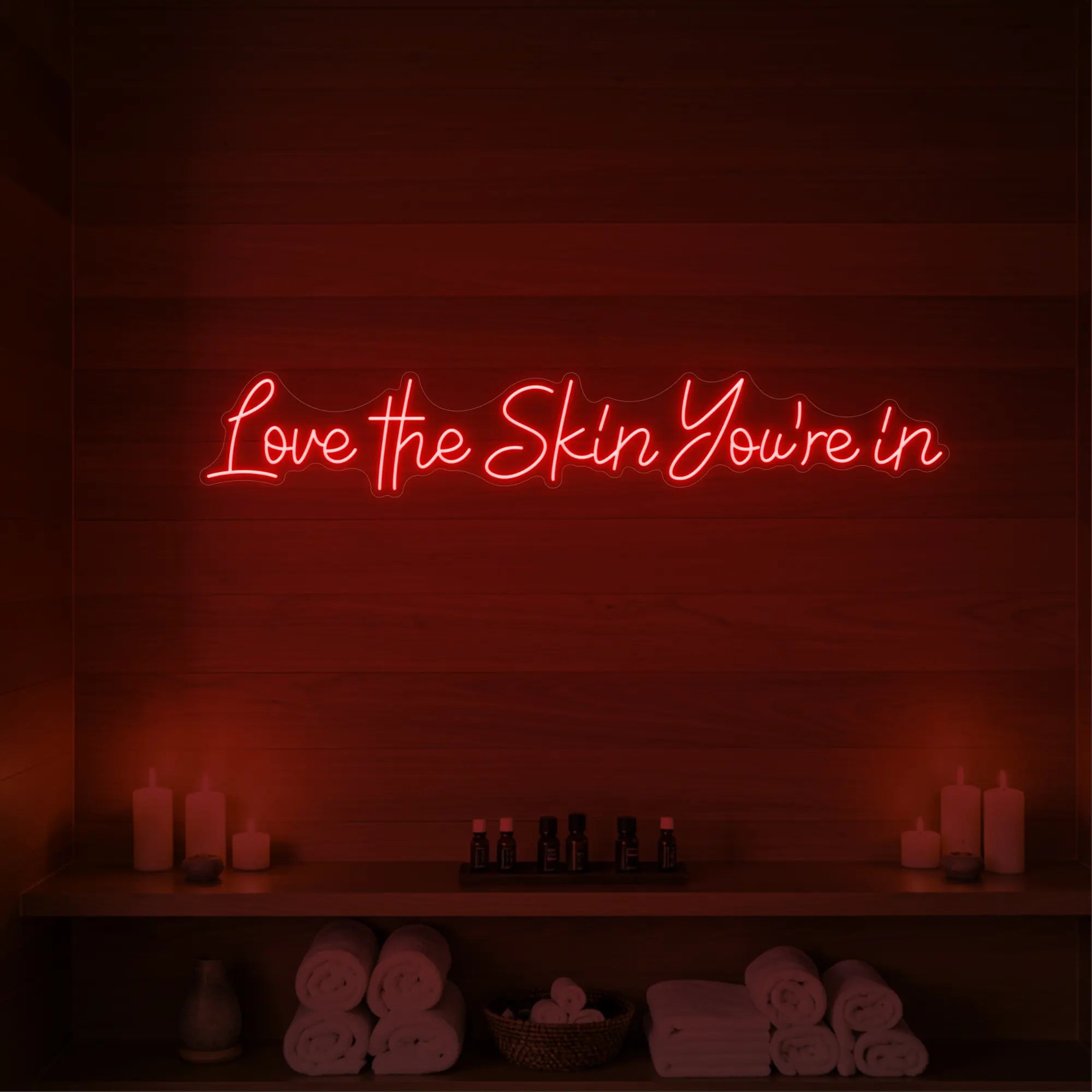 Photo of the 'Love the Skin You're In' neon sign glowing in red against a styled interior wall.