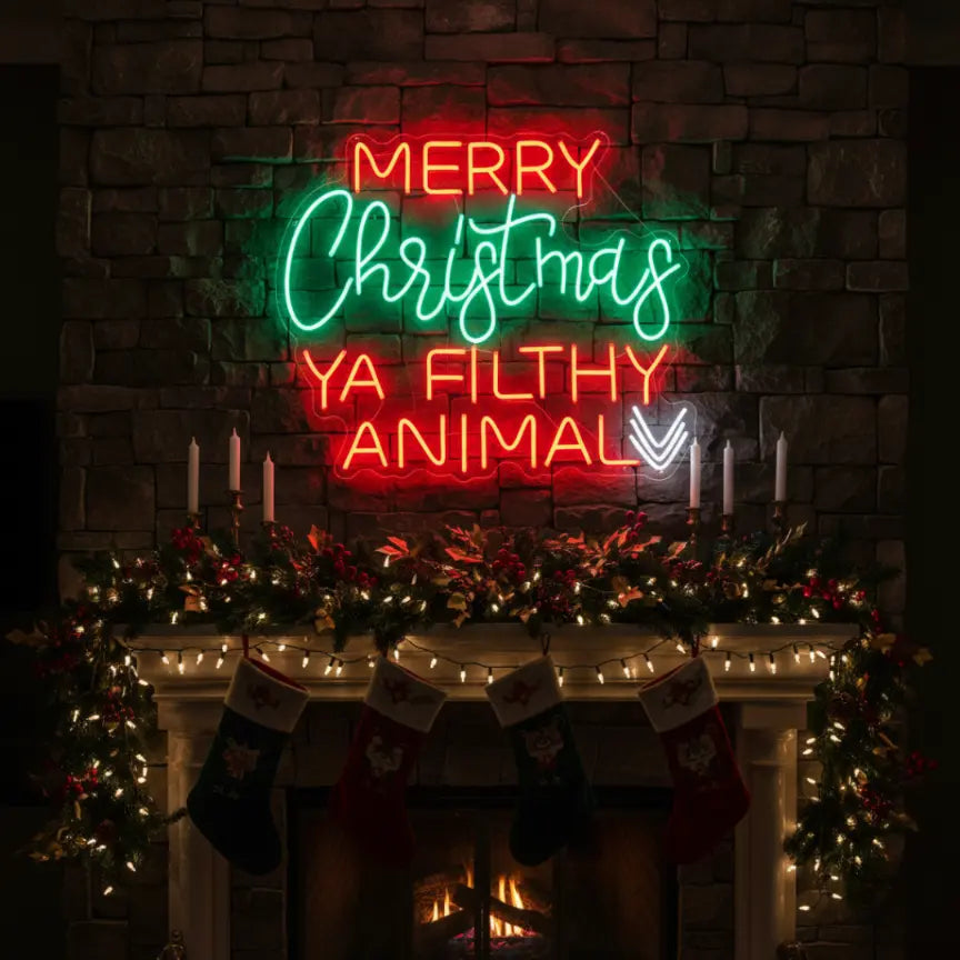 Photo of the 'Merry Christmas Ya Filthy Animal' neon sign glowing in multicolor against a styled interior wall.