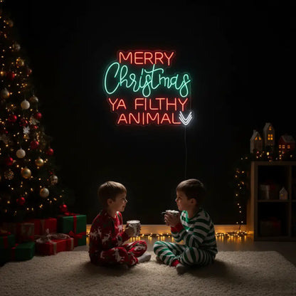 Photo of the 'Merry Christmas Ya Filthy Animal' neon sign glowing in multicolor against a styled interior wall.