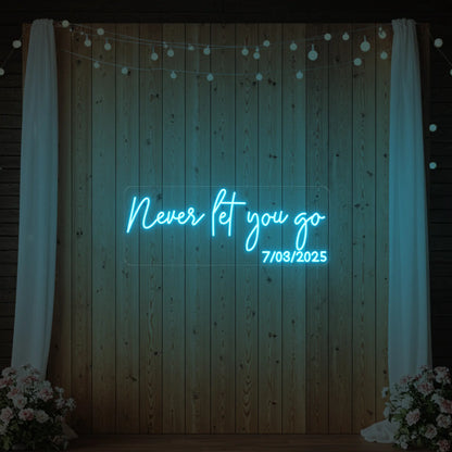  'Never Let You Go' neon sign glowing in ice blue against a styled interior wall.